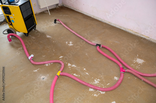 Floor drying after a burst water pipe using a dehumidifier with water damage restoration pipes