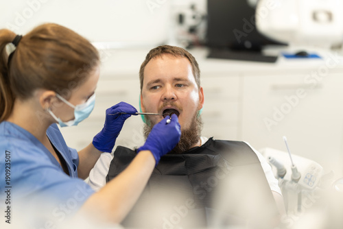 Tableau sur toile Man sits anxiously in a chair at a dentist appointment