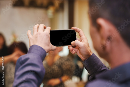 Man takes photo at event with smartphone in indoor setting