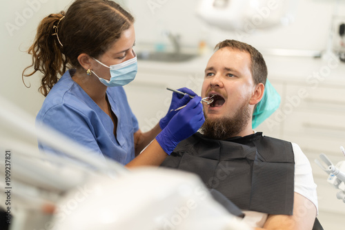 Tablou pe pânză Man sits anxiously in a chair at a dentist appointment