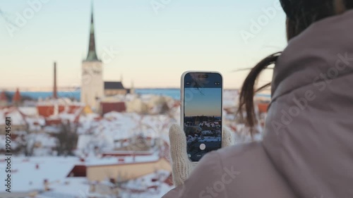 Person holding phone and taking picture of city in winter during sunny day
