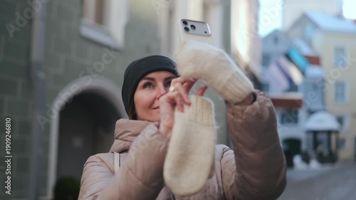 Woman takes a picture with her phone in a city street during daylight hours