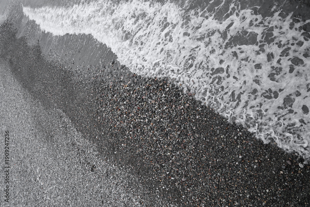 Obraz premium Black Sea. water wave on pebble beach shore. Batumi, Georgia. top view on blue aqua surface. top aerial view. Sea blue water wave on pebble beach shore. diagonal.