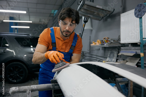 Photos Auto body technician sanding car panel in workshop - repair and refinishing proc