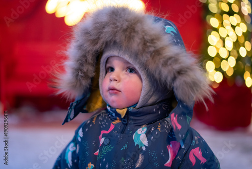 Warmly dressed child enjoying the festive sparkle of glowing holiday decorations