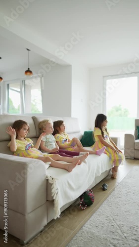 Four young sisters watching television in living room