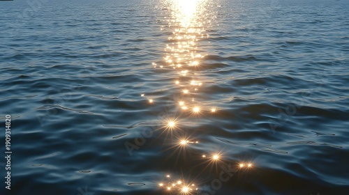 Bright sunlight creates a shimmering path on the gently rippling blue green water surface