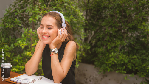 Young carefree attractive Asian woman enjoy to listening music in garden