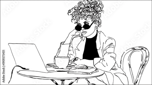 A woman is sitting at a table with a laptop and a cup of coffee
