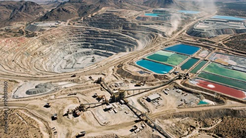 Open pit copper mine terraced excavation with turquoise green red evaporation pond rare earth heap leach ponds heavy equipment industrial scale