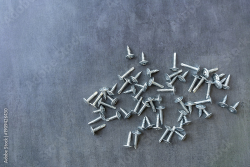A metal self-tapping screw with a press washer is scattered on the table.View from above.A tool for mounting.