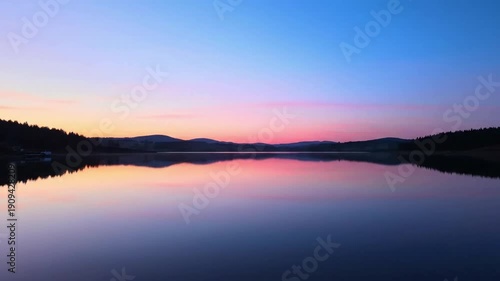 Tranquil Morning Waterscape Focusing on the still, cool waters of the lake as the first light of dawn gently illuminates the scene, emphasizing the peaceful and undisturbed natural environment.