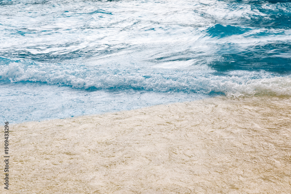 Obraz premium Gentle ocean waves lapping against a sandy beach under a bright sky, showcasing the natural beauty of coastal scenery
