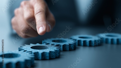 Hand adjusting metal gear on table representing change management transformation, strategy alignment, process optimization and leadership intervention.