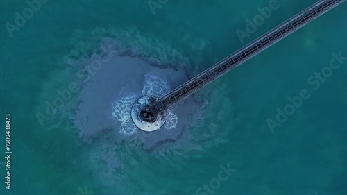 Aerial view of a metal structure in turquoise water, surrounded by a plume of sediment contrasting with the clear water, Arizona, United States.