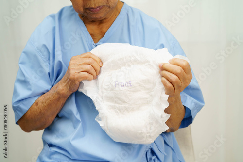 Asian senior woman patient wearing adult incontinence diaper pad in hospital.