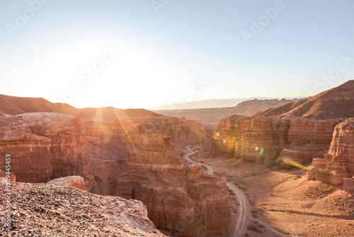 Winding road crossing Charyn Canyon in Kazakhstan, illuminated by the warm light of the sunrise sun Charyn Canyon, Valley of Castles. The excellence of Kazakhstan. Panorama of natural unusual landscap