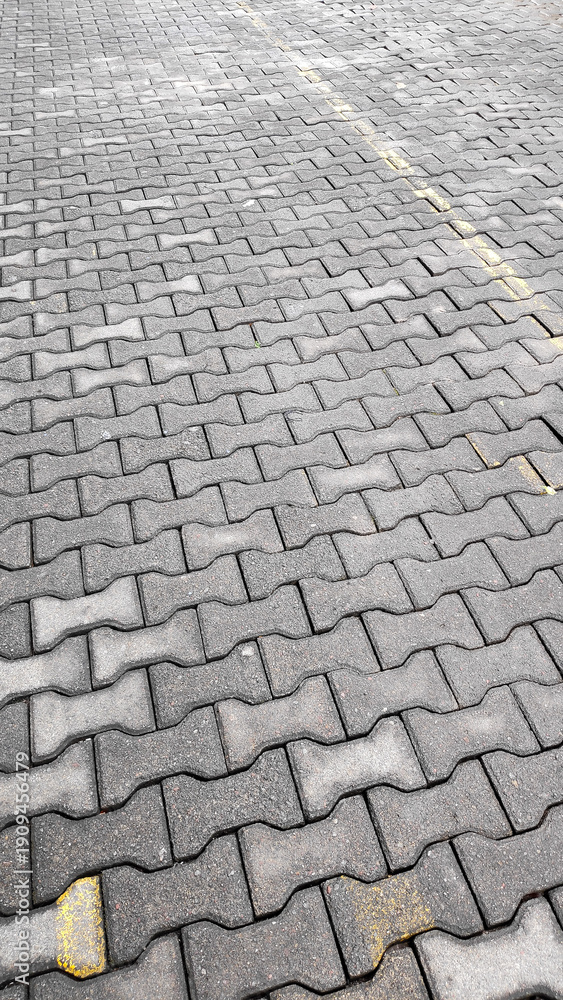 Fototapeta premium Close up view of grey interlocking concrete pavers with yellow parking lines clearly visible.