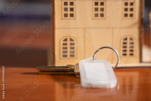 Wallpaper Mural A key is laying on a wooden table next to a house model. The key is silver and has a white tag on it Torontodigital.ca