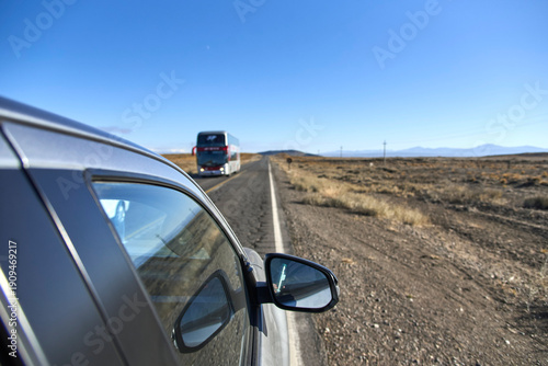 Roadtrip scene, driving through the province of Neuquen, Argentina. In the foreground, the side of the car; in the background, a bus traveling in the opposite direction on the road.