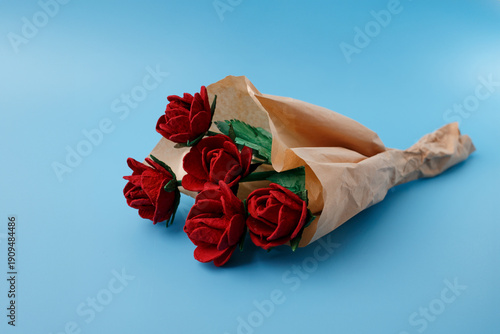 Handmade red roses bouquet from recycled paper egg cartons in brown kraft wrapping on blue background. Sustainable gift for Valentines Day Mothers Day eco friendly florist business decor concepts