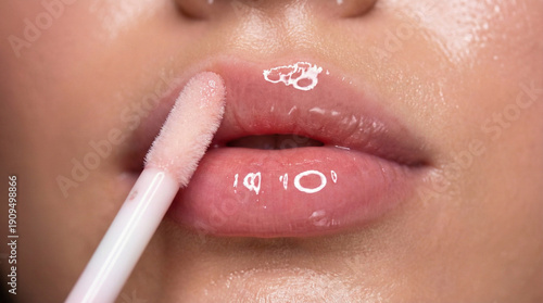 Close up of glossy pink lips with application of liquid lip gloss using wand applicator, professional makeup and beauty routine