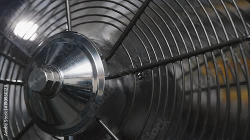 Close-up of a metallic fan with a circular grille design  