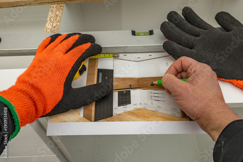 A carpenter makes corrections to a kitchen furniture design, a man draws a kitchen furniture design,