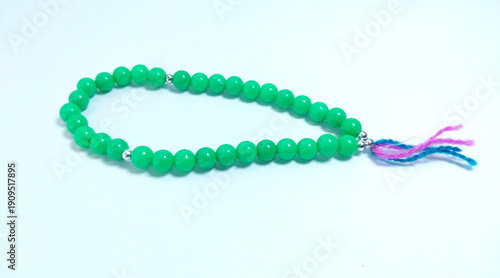 Islamic tasbih (string of prayer beads) made of green plastic material isolated on bright background.