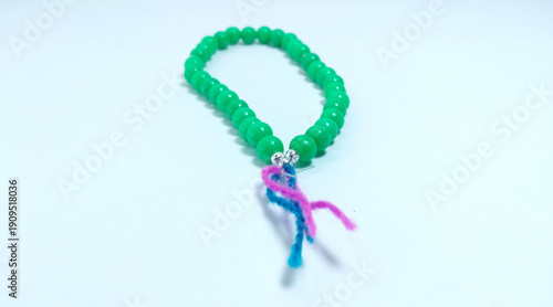 Islamic tasbih (string of prayer beads) made of green plastic material isolated on bright background.