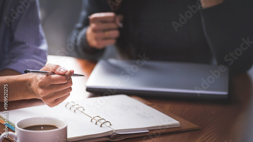 Hand of business people with pen and data sheet at meeting. Woman learning and reading a book together at coffee shop or cafe in the morning, vintage tone
