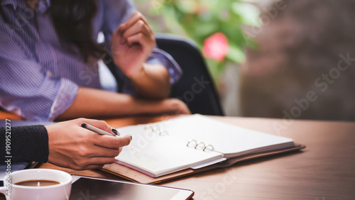 Hand of business people with pen and data sheet at meeting. Woman learning and reading a book together at coffee shop or cafe in the morning, vintage tone