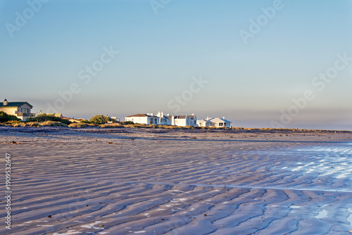 Homes next to a wide empty beach at low tide in the early morning on the West Coast near Dwarskersbos in the Western Cape, South Africa