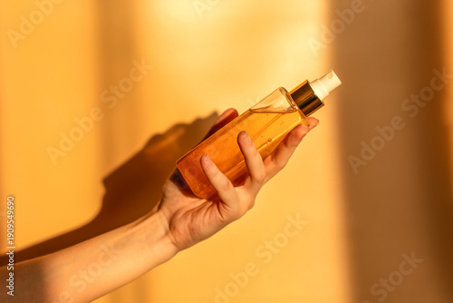 Hand, face or body lotion. A woman's hand holding a mock-up of a glass jar of lotion on a light background. The concept of cosmetics, skin care, nutrition and hydration.