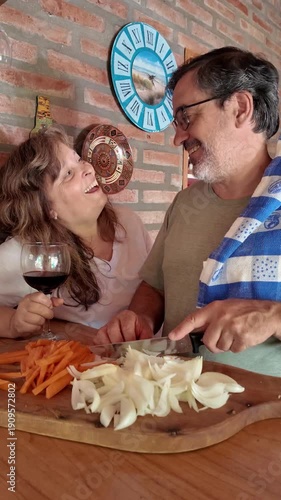 Mature caucasian couple laughing while cooking together at home
