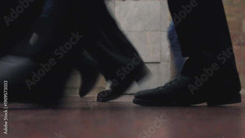 Low angle ground shot of diverse people walking in subway station. Focus on legs and colorful shoes moving in crowd. Busy metropolitan lifestyle and urban public transport concept.