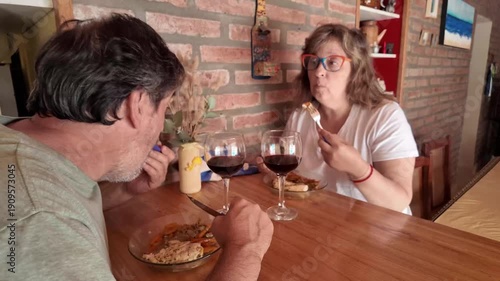 Senior couple toasting with red wine during home dinner