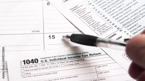 Close-up view of a person preparing to fill out the united states individual income tax return form 1040 on a calendar background