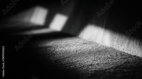A narrow dimly lit corridor showcases stark contrasts of light and shadow with rough textured concrete walls and floor i