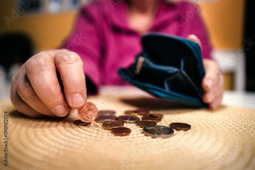 Alte Frau zählt Kleingeld an einem Tisch