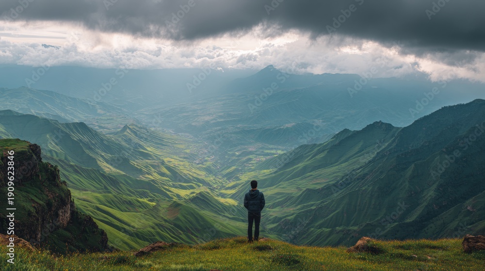 Obraz premium Man with his back turned on the top of a mountain
