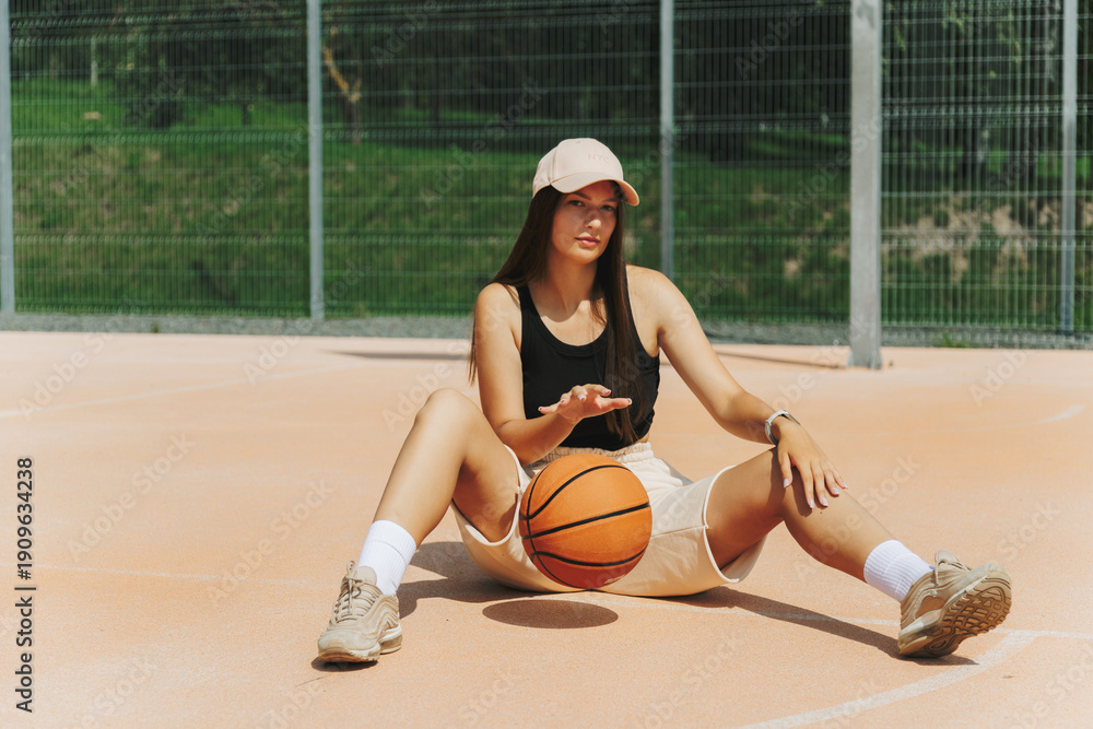 Naklejka premium Woman Sitting With Basketball On Outdoor Court. Casual Sport And Fitness Concept.