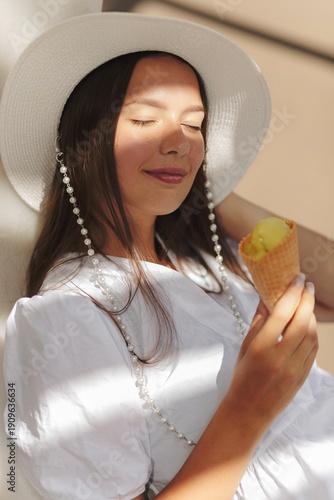 Wallpaper Mural Young caucasian woman eating ice-cream during summer sunny day. Brunette wears white dress and hat Torontodigital.ca