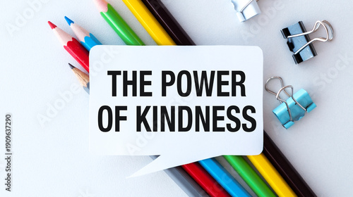 The Power of Kindness against the background of colored pencils and clips on a white table