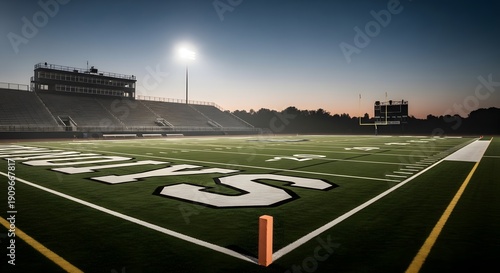 Detailed view of yard line numbers on turf with empty grandstands and a scoreboard in the background.