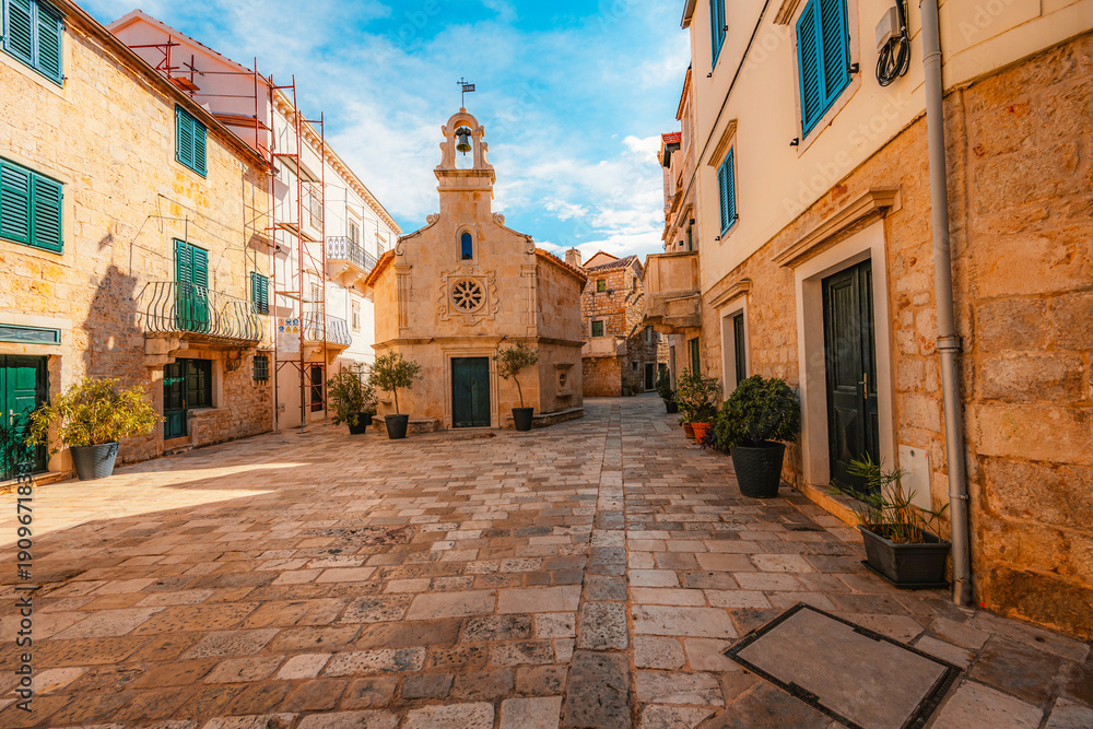 Fototapeta premium Jelsa town on Hvar island, with traditional Dalmatian stone architecture and boats moored in the harbor, Croatia.