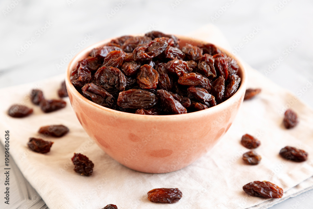 Fototapeta premium Organic Dried Chilean Dark Raisins in a Bowl, side view. Copy space.
