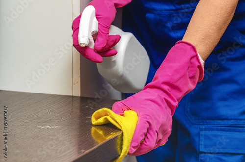 Order cleaning services and modern office care concept. Worker in blue overalls and pink gloves.