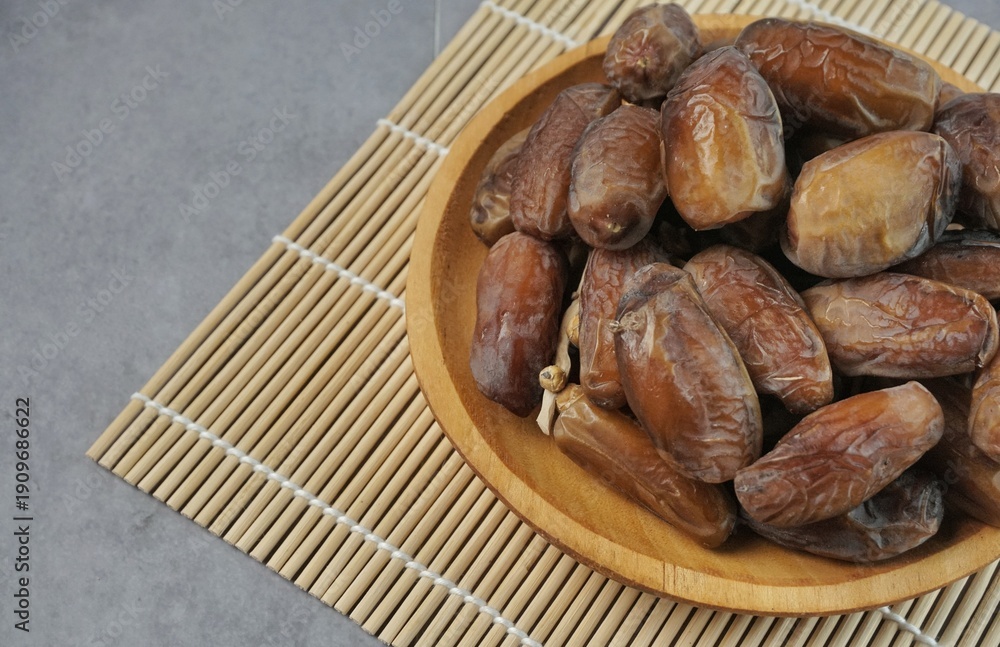 Obraz premium A pile of dried dates lies in a copper plate. Three dates lie side by side