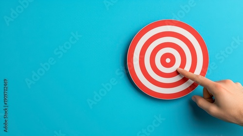 Wallpaper Mural A hand points to the bullseye of a red and white target against a blue background, symbolizing focus and precision. Torontodigital.ca